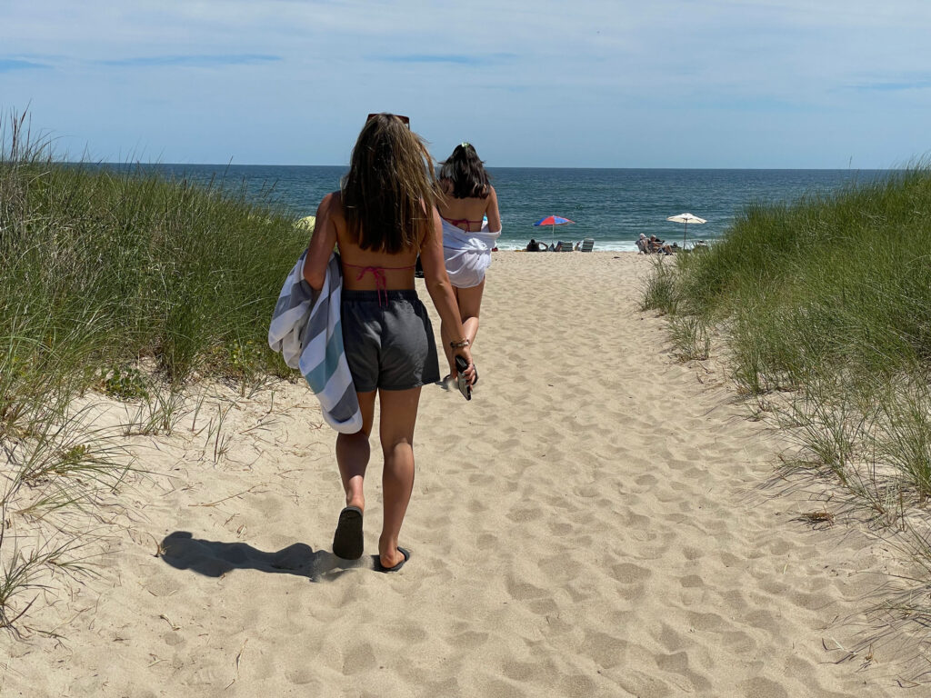 Two girls walking to the ocean beach in East Hampton Village.